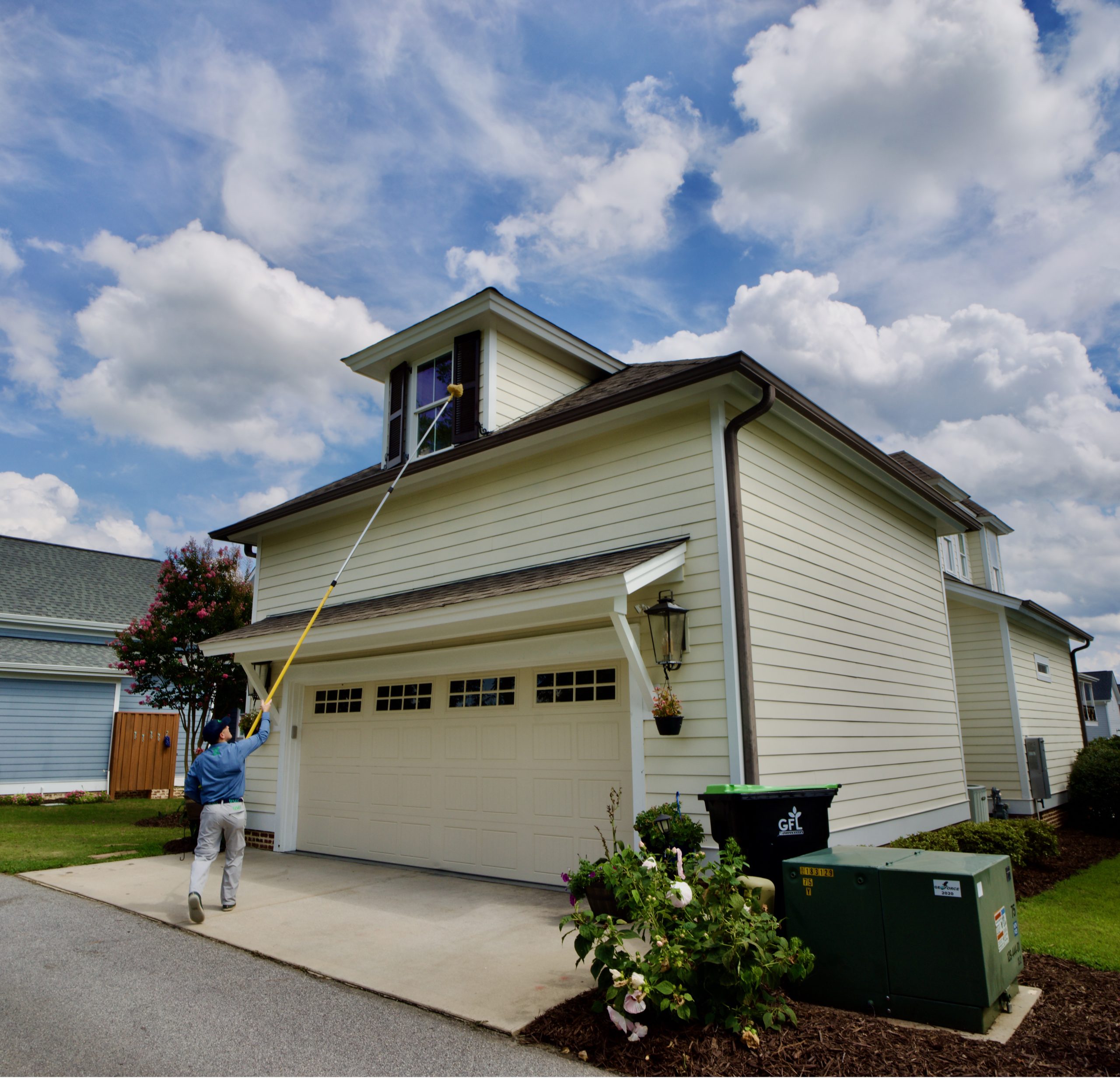 Removing spider webs from a house dormer.
